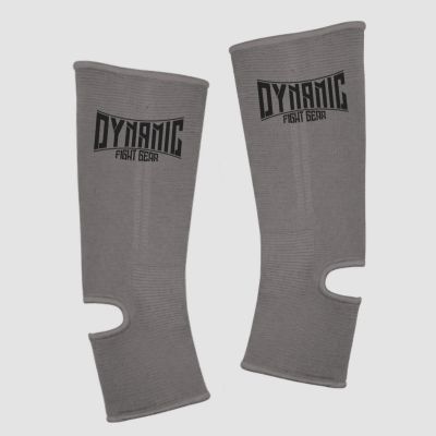 Pair of gray shin guards with the Dynamic Fight Gear logo, contoured with strap openings for leg protection